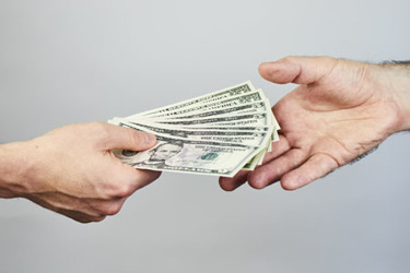 Two-hands-exchanging-dollars-GettyImages-974812152