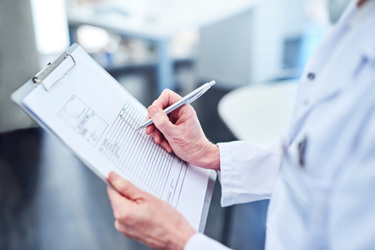 Medical professional filling out paperwork-GettyImages-1132204239
